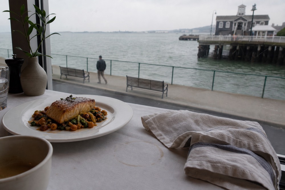 Plated dinner course on the Odyssey with harbor view through window