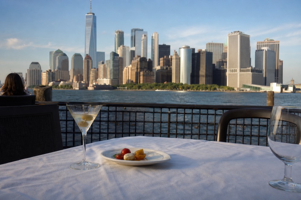 Cocktail and appetizer on white tablecloth with Boston skyline in background