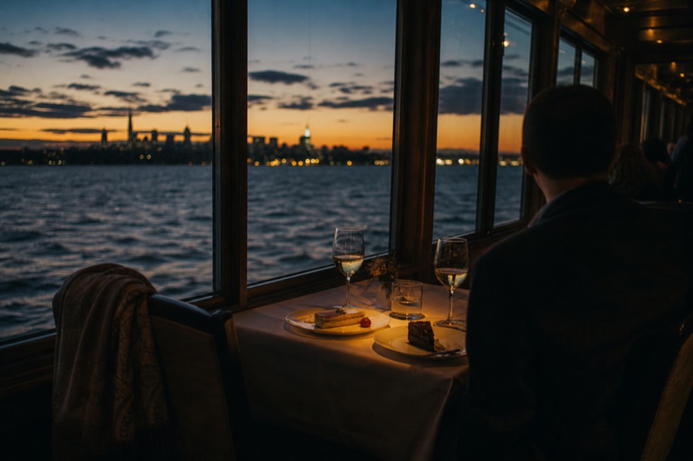 Couple at private table on Odyssey dinner cruise with Boston skyline through window