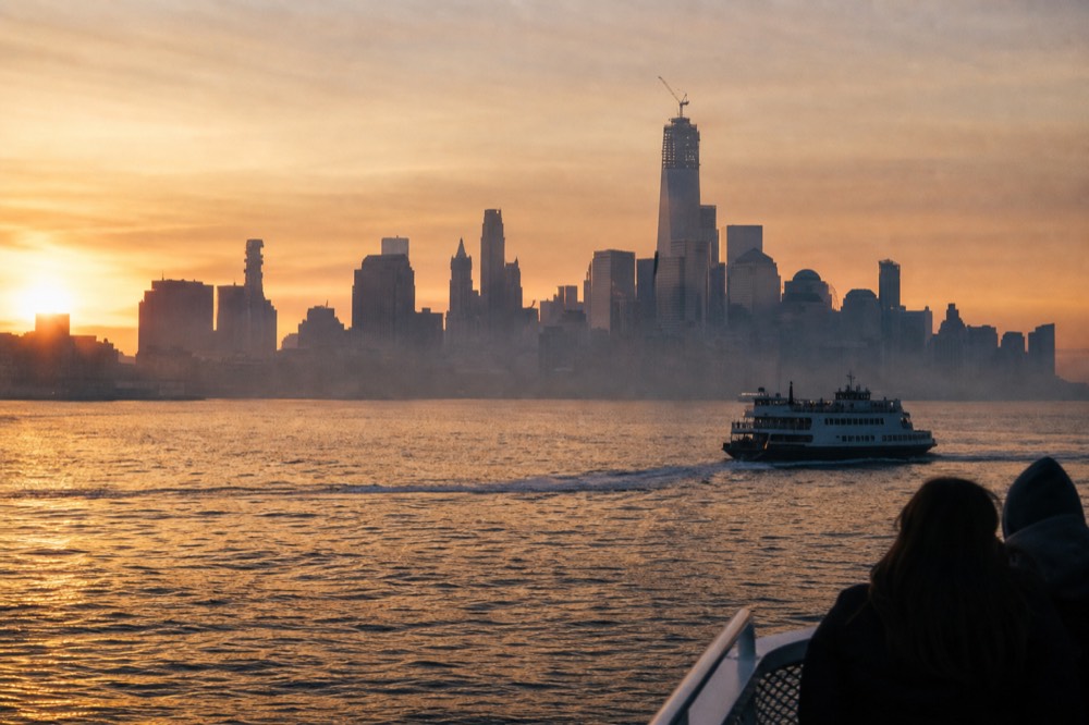 Boston skyline seen across open harbor water at sunset