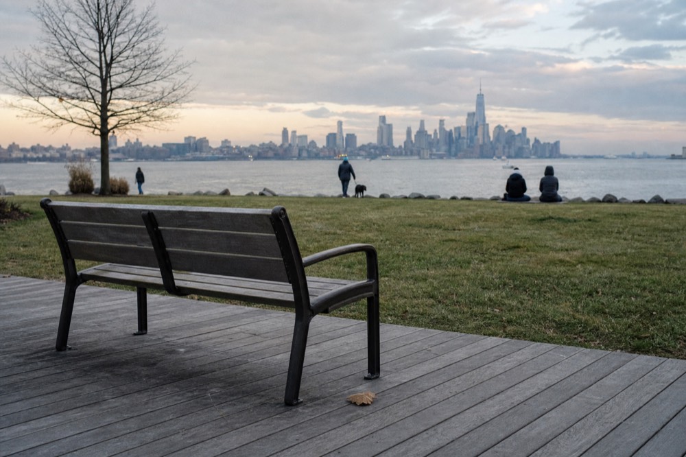 Empty waterfront boardwalk bench overlooking Boston Harbor in evening light