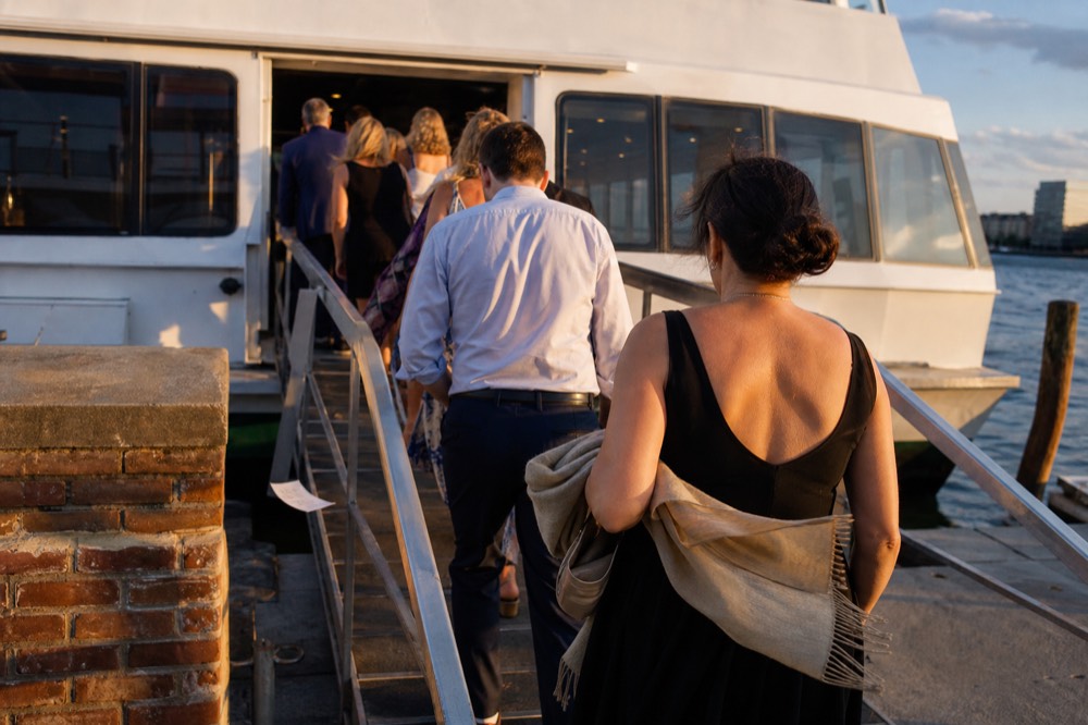 Passengers boarding a dinner cruise vessel at a Boston pier in the early evening