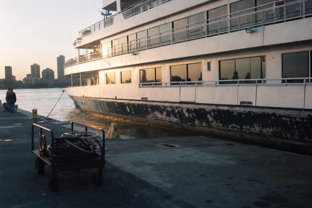 A large multi-deck cruise vessel docked at a Boston waterfront pier in evening light