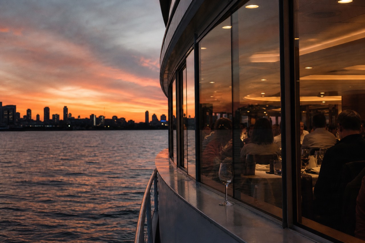 Boston Harbor dinner cruise at sunset, with skyline and tables
