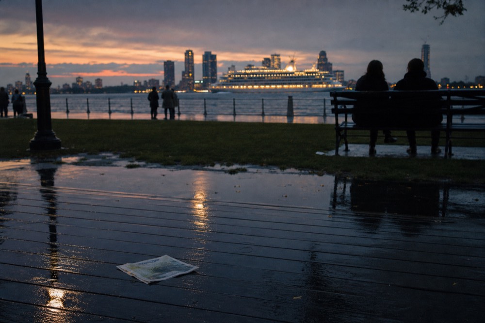 A Boston waterfront at dusk with a cruise vessel lit up in the harbor