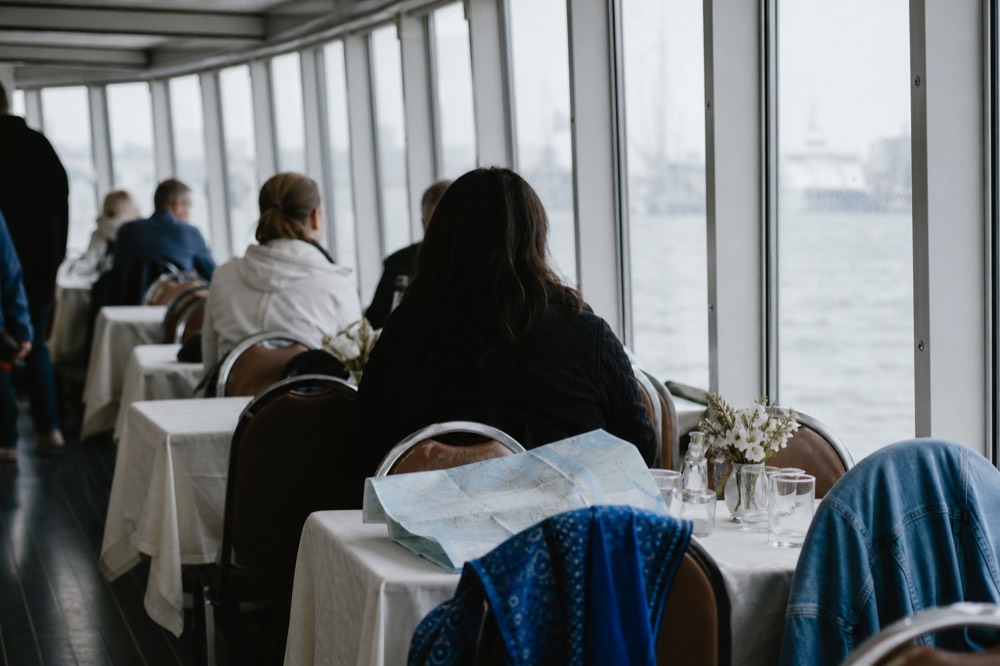 Light jackets and scarves hanging on the back of dining chairs inside a climate-controlled cruise deck