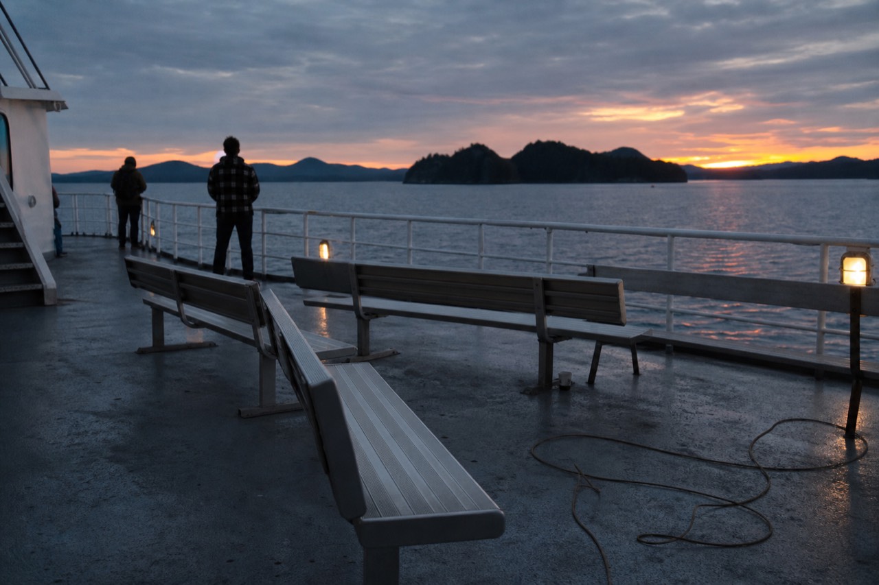 Open-air deck of a dinner cruise vessel on Boston Harbor at dusk