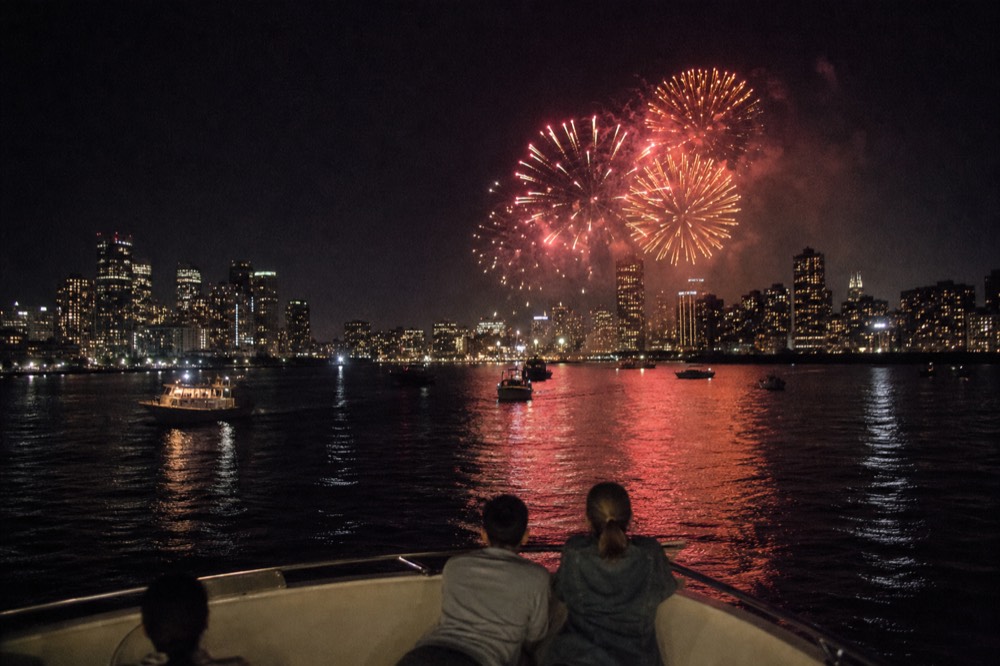 Fireworks over Boston skyline with harbor reflection