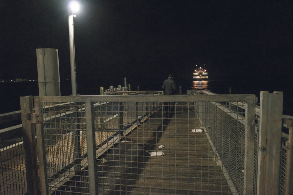 An empty gangway and closed boarding gate at a Boston cruise pier at night