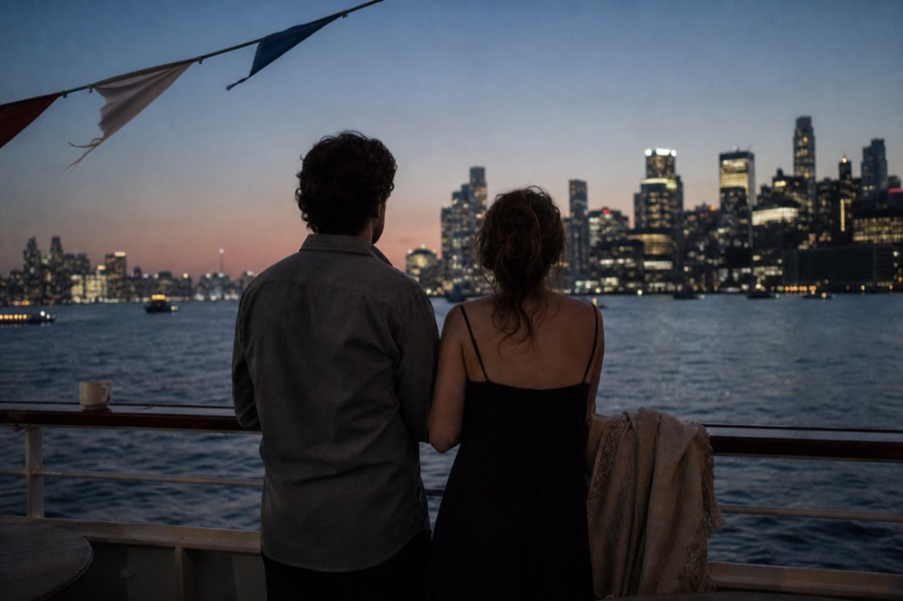 Couple at a cruise rail watching the Boston skyline light up after dinner