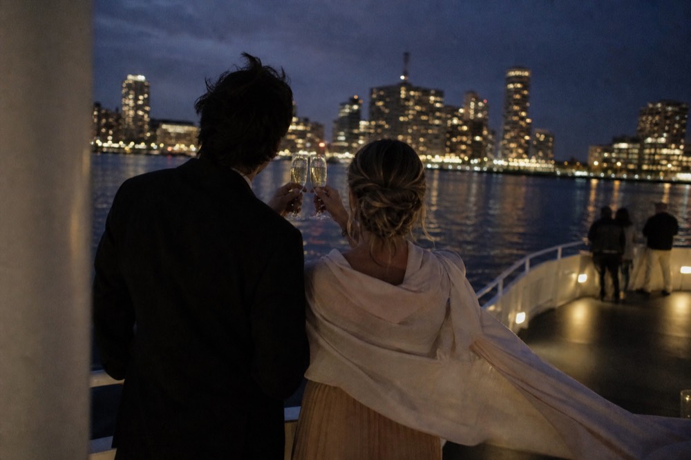 A couple toasting with champagne glasses on an evening harbor cruise