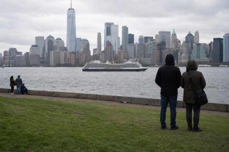 Downtown Boston skyline seen across the harbor from a waterfront park as a cruise boat passes
